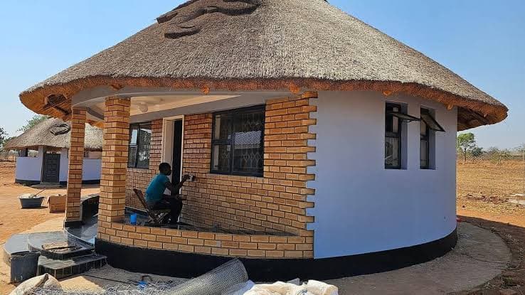 A round thatched cottage in face brick with a covered verandah