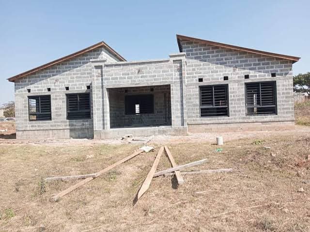 A concrete block house shell with mono-pitch roofs and steel window frames